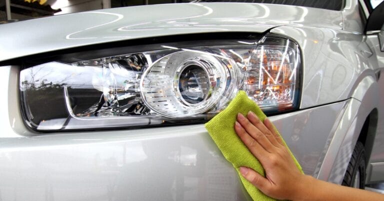 Cleaning a silver cars headlight with a green cloth at Iligan Carwash.