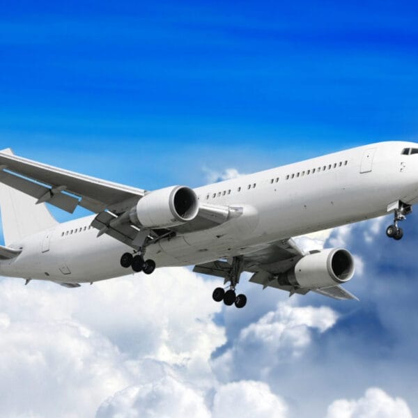 White passenger airplane soaring above white clouds with a clear blue sky backdrop, reminiscent of Iligan flights.