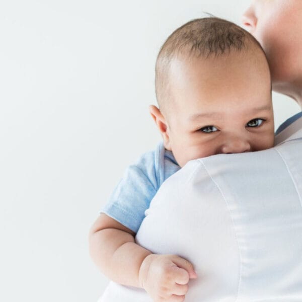 Adult holding a baby against their shoulder, baby looking at the camera, reminiscent of a serene moment in Pedia Iligan.