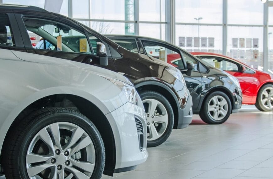 row of four registered cars iligan in a bright showroom, large windows and tires stacked in the background.