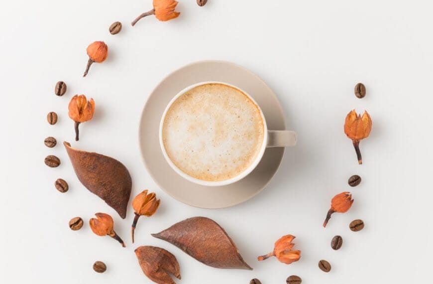 a cup of philippine coffee on a saucer sits among dried leaves, orange buds, and beans—perfect for makati mornings.