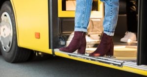 person in rolled up jeans and burgundy boots steps off a yellow bus at an iligan city transportation terminal.