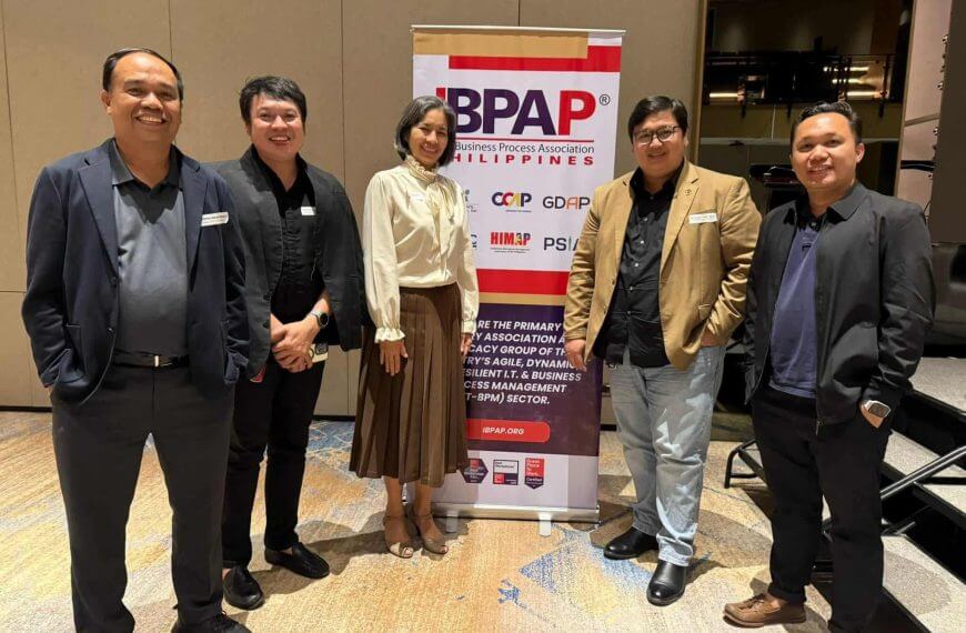 five people in business attire smile beside a bpap banner at an iligan it bpm event.