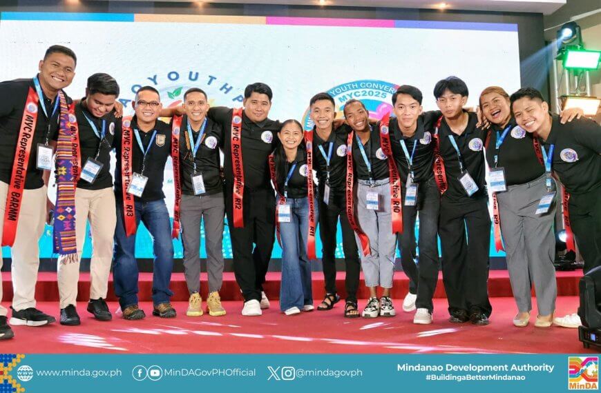 eleven smiling young adults in black shirts pose together on stage at a mindanao youth event.