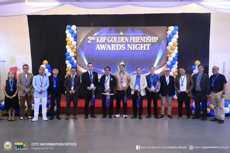a group of 15 people stand on stage with medals at the kbp golden friendship awards in cagayan de oro.