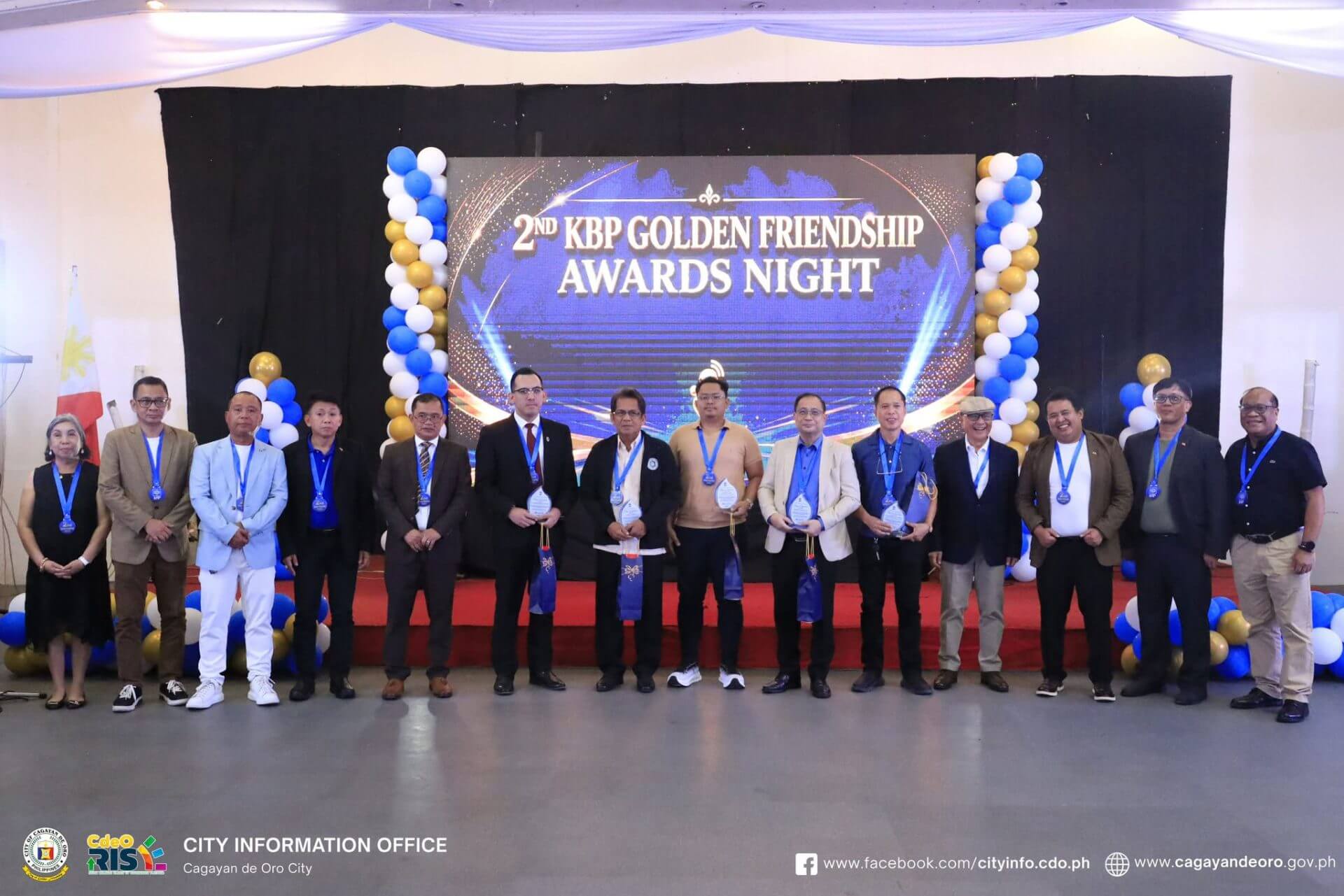 a group of 15 people stand on stage with medals at the kbp golden friendship awards in cagayan de oro.